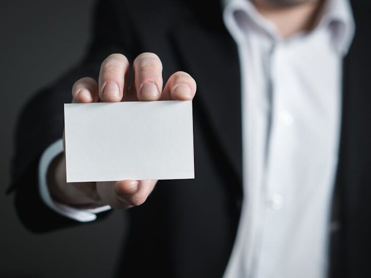 A man in a suit presenting a blank business card for corporate usage.